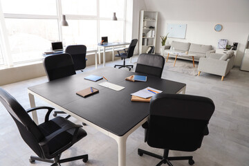 Table, armchairs, board and stationery prepared for business meeting in stylish conference hall