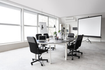 Interior of stylish conference hall with table, window, screen board and armchairs