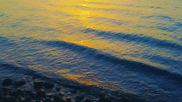 Onde del mare a riva che si infrangono sulle rocce al tramonto