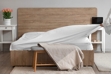 Woman making bed in modern bedroom