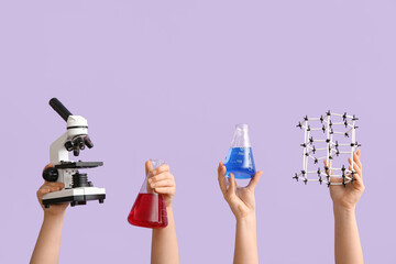 Female hands holding filled flasks with molecular model and microscope on lilac background....