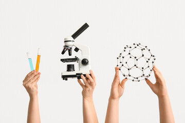 Female hands holding filled test tubes with microscope and molecular model on white background....