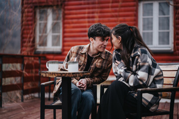 Young loving couple sitting closely together on their porch at home, sharing a warm, intimate moment over coffee.