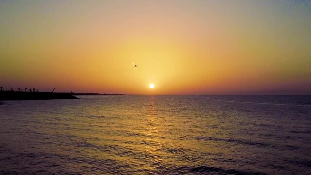 Aereo da turismo che vola al tramonto sopra al sole con mare calmo e con il  promontorio del Gargano sullo sfondo 