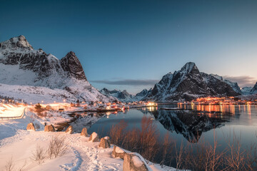 Fishing village illuminated in mountain valley reflection on winter at dawn