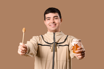 Male beekeeper with honey and spoon on brown background