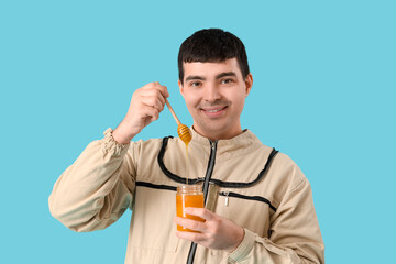 Male beekeeper with honey and spoon on blue background, closeup
