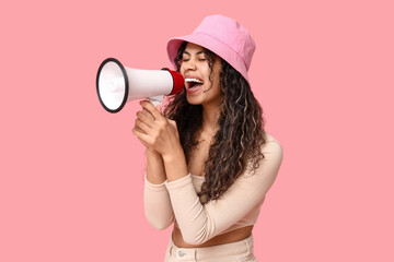 Screaming African-American woman with megaphone on pink background