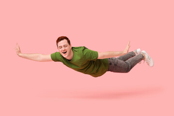 Joyful young man flying on pink background