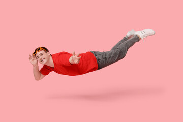 Joyful young man in sunglasses flying on pink background