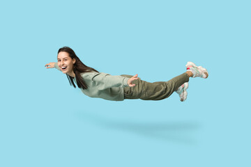Joyful young woman flying on blue background