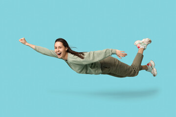 Joyful young woman flying on blue background