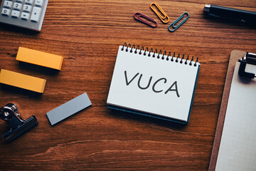 There is notebook with the word VUCA. It is an abbreviation for Volatility, Uncertainty, Complexity, Ambiguity as eye-catching image.