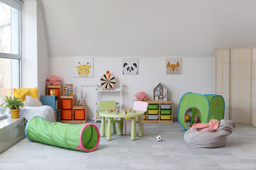 Fototapeta premium Interior of modern children's room with table and play tunnel