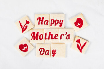 Mother's Day dessert. Cute Delicate square shortbread cookies with red marmalade filling in the shape of the words happy mother's day and flower and a heart. White background. Top view