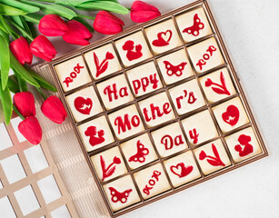 Mothers Day. Modern square shortbread cookies with marmalade filling in a themed form, happy mother's day, mom, flower, butterfly, mother and child, hearts. In a wooden gift box. With red tulips