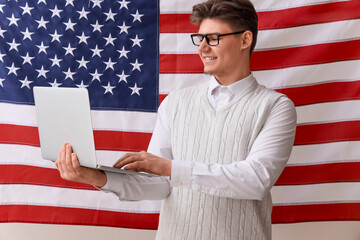 Male programmer with laptop standing against USA flag background