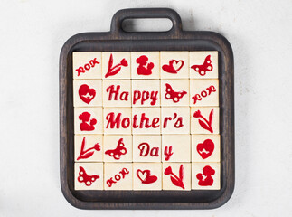 Mothers Day dessert. Delicate square cookies with red marmalade filling in a thematic form, happy mother's day, mom, flower, butterfly, mother and child, hearts. On a wooden plate. Top view