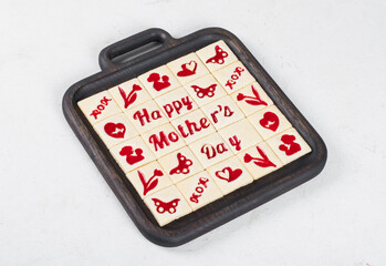 Mothers Day. Delicate square shortbread cookies with marmalade filling in a thematic form, mother's day, mom, flower, butterfly, mother and child, hearts. On a wooden plate. White background. Close up