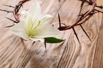 White lily and crown of thorns on wooden background, closeup
