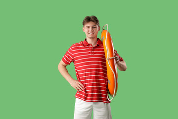 Male lifeguard with ring buoy on green background