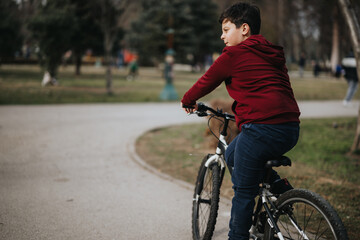 A young boy cycles in a city park, enjoying leisure time and healthy recreation in fresh air...