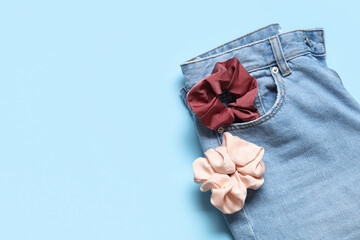 Jeans with trendy silk scrunchies on blue background