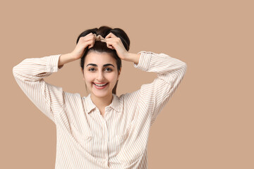 Happy smiling woman with bun hairstyle and silk scrunchy on beige background