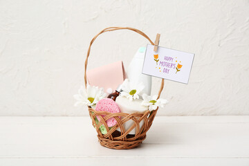 Gift basket with cosmetic products, flowers and card for Mother's Day celebration on light wooden...