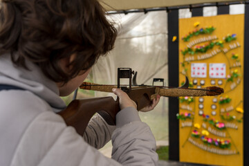 A teenager shoots a recreational crossbow at a shooting range. Focus on the foreground.