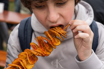 Teenager eating freshly cooked spiral chips.