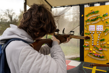 A teenager shoots a recreational crossbow at a shooting range. Focus on the foreground.