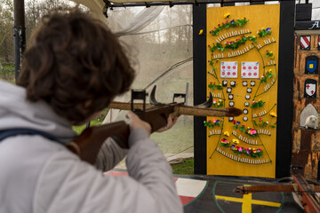 A teenager shoots a recreational crossbow at a shooting range. Focus on the background.