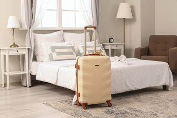 Interior of hotel room with suitcase near bed