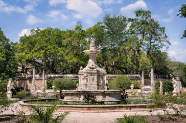 Fototapeta na wymiar Bright sunny noon view of the exquisite carved fountain in the Fountain Garden of Villa Vizcaya Museum. The Vizcaya Museum and Gardens is the early 20th-century Vizcaya estate also including extensive