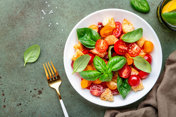 Simple italian salad with with stale bread, cherry tomatoes, olive oil, sea salt and green basil white plate, stone table background, top view - 792153670