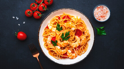 Cooked spaghetti pasta with big shrimp and tomato sauce, black table background, top view - 792154012