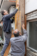 Worker is installing and assembling column formworks for concrete filling at building site. Wooden...