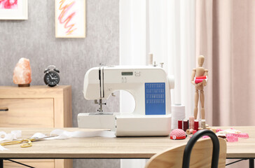 White sewing machine, cloth, craft accessories and mannequin on wooden table indoors