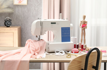 White sewing machine, cloth, craft accessories and mannequin on wooden table indoors