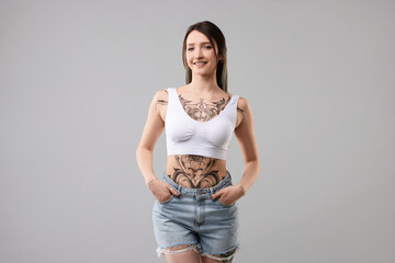 Portrait of smiling tattooed woman on grey background