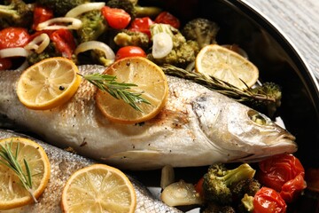Baked fish with vegetables, rosemary and lemon on table, closeup