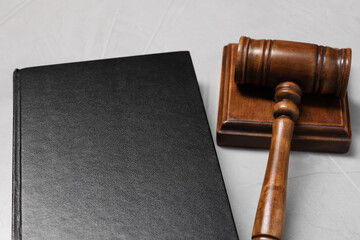 Law. Book, gavel and sound block on light table, closeup