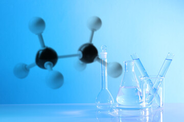 Laboratory glassware and molecule model on blue background