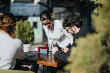 Multiracial business colleagues engaged in a meeting at an outdoor coffee bar, strategizing on...