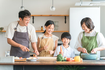 家のキッチンで子供と一緒に料理・クッキング・お手伝いする子供と夫婦・親子・家族
