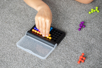 Child's hand piecing together a bead puzzle, enhancing fine motor skills and problem-solving.