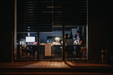 Business people working late at night, collaborating, discussing project details, sales strategies,...
