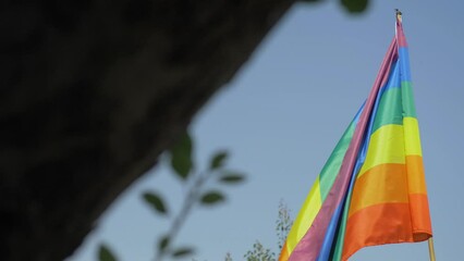 Rainbow LGBT flag stands as symbol of love and acceptance in all its forms against vastness of sky. Reminds to embrace our differences and stand together as allies in solidarity. Colorful pride flag
