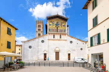 Fototapeta na wymiar Piazza San Frediano with the facade and bell tower of the San Frediano Basilica, a Romanesque church with golden mosaic facade, inside the walled medieval town of Lucca, Italy. 